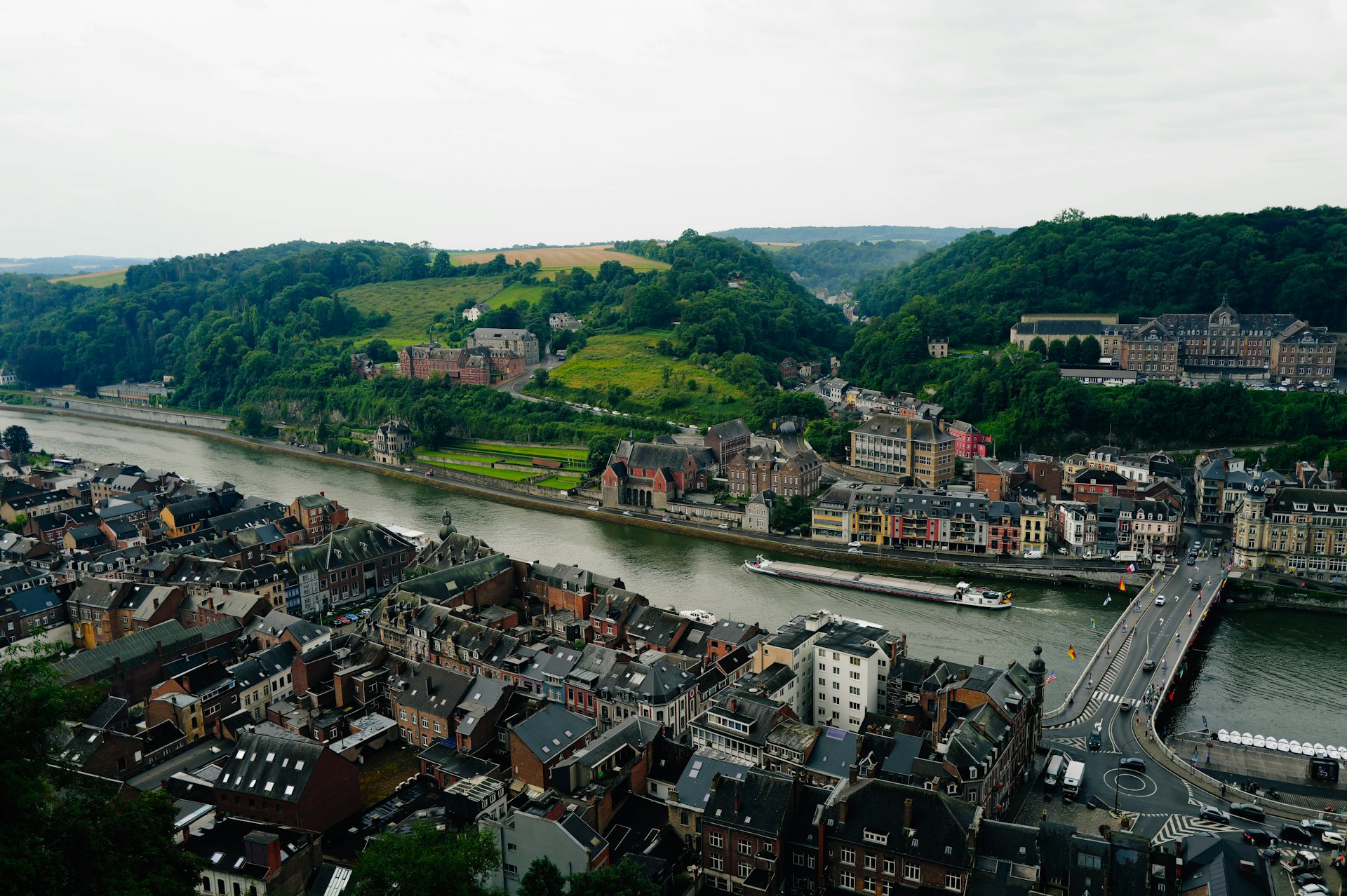 A river running through a city next to a lush green hillside
